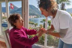 Infermiera a domicilio assiste un’anziana a Lugano con vista sul lago